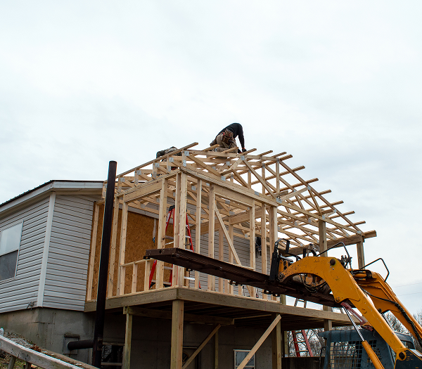 Construction worker building wooden house framework.