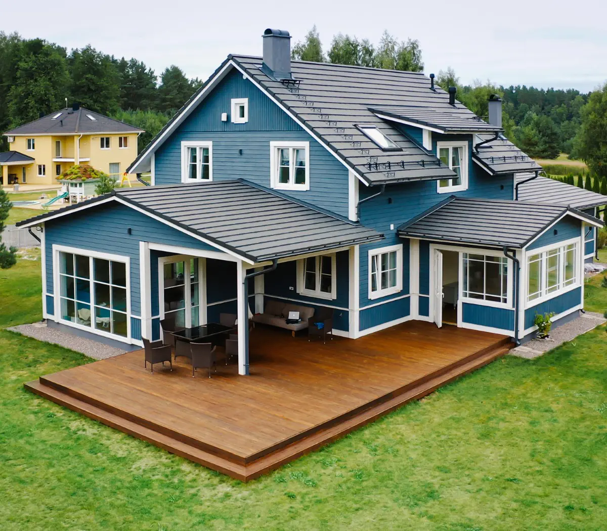 Blue house with wooden deck and chairs.